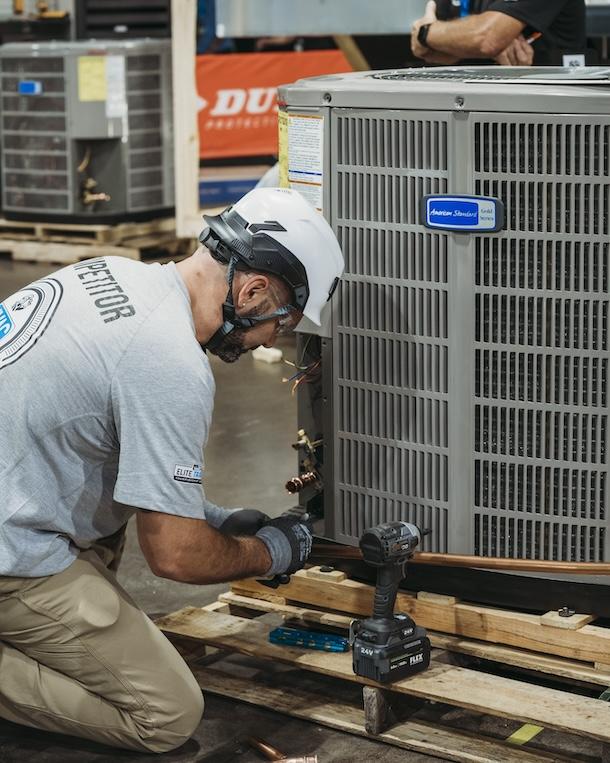 A technician is working on an American Standard air conditioner.