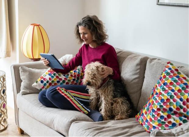 A woman reads a document while petting her dog.